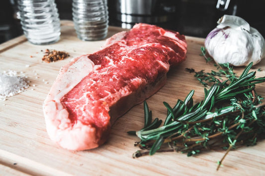 Corte de carne crua sobre tábua com alho e alecrim, pronto para o churrasco